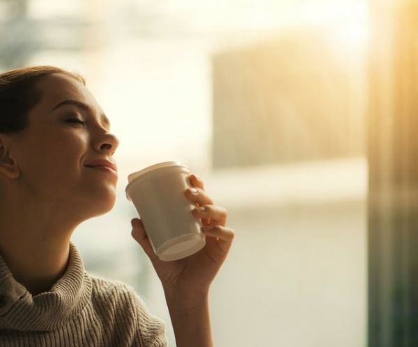 Γυναίκα απολαμβάνει το καφέ της μπροστά στο παράθυρο